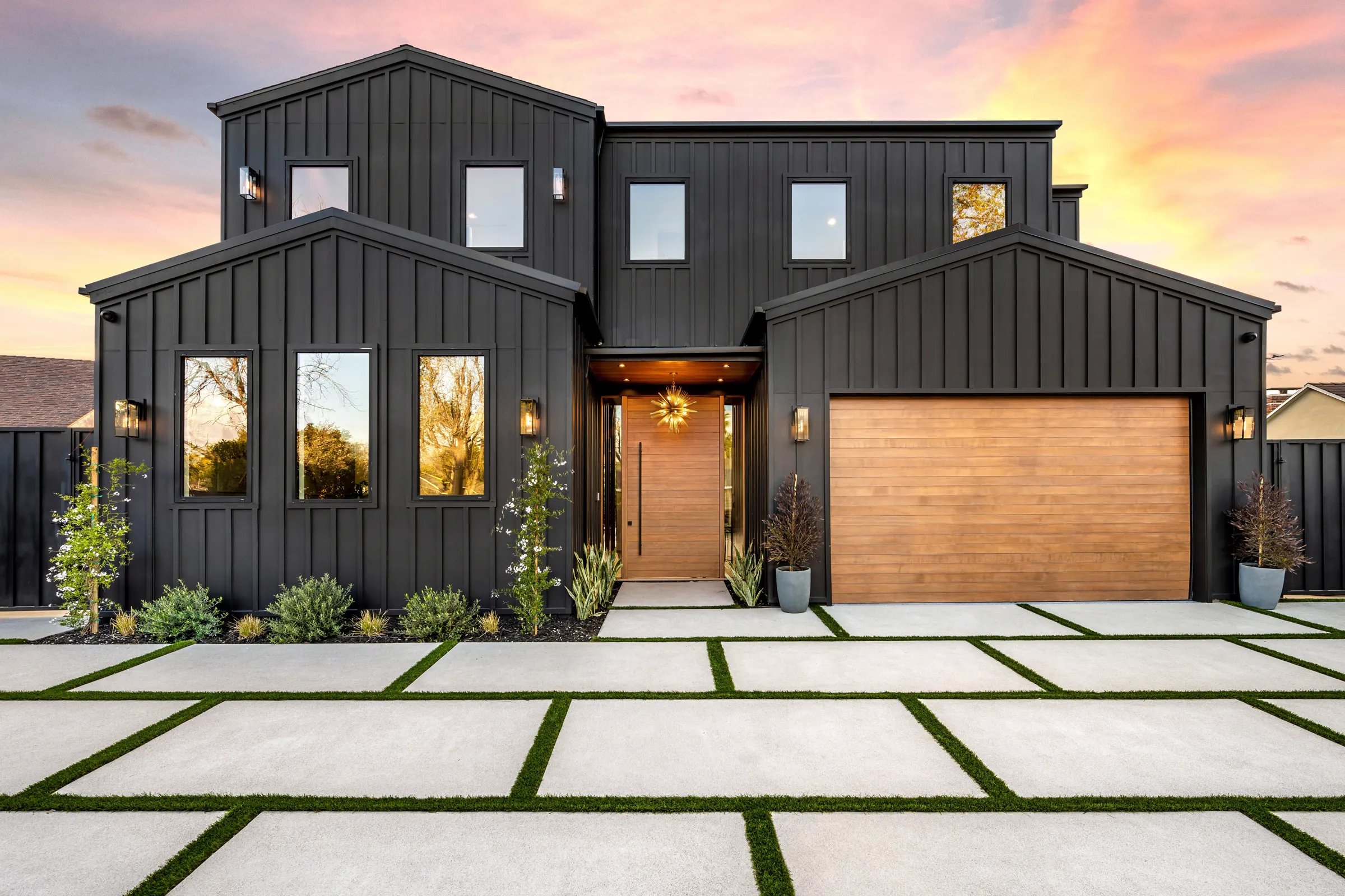 Modern black home with a wood front door at sunset (illustrative, not an actual listing)