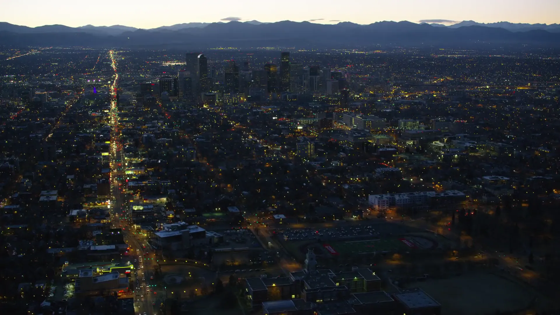Denver skyline at night with the Rocky Mountains beyond